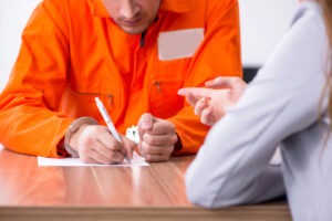 A DUI lawyer in Marion County discussing legal options with a client who is handcuffed and wearing an orange jumpsuit.